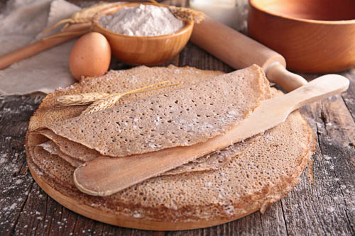 A stack of dairy free buckwheat pancakes / crepes with ingredients in the background