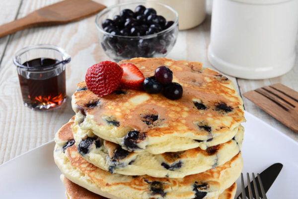 Lemon berry pancakes with blueberries and strawberries, maple syrup.