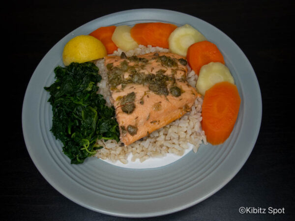 Plate of baked salmon with capers on a bed of brown rice with vegetables