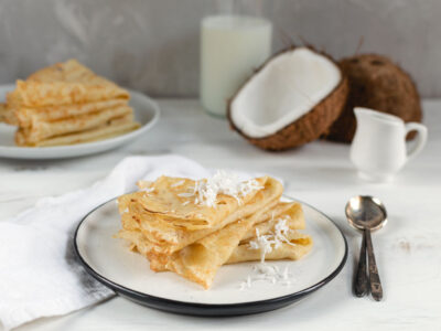 A plate of coconut flour crepes topped with shredded coconut