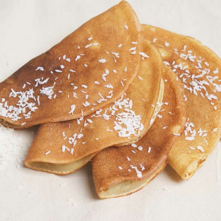 A plate of coconut flour crepes topped with shredded coconut