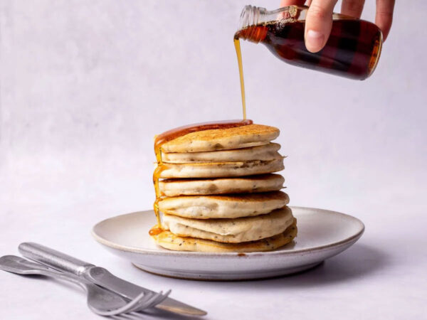 stack of gluten-free pancakes with maple syrup being poured on the m