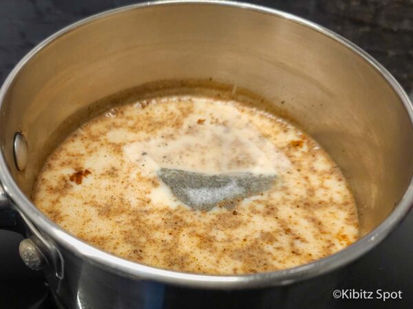 Chai latte with a black tea bag being made on the stovetop