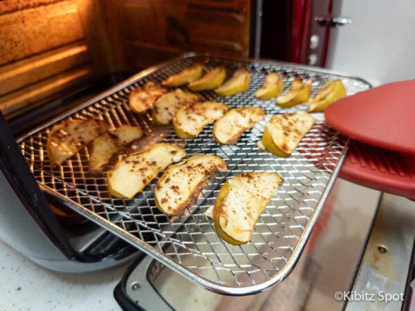 Air fryer apples and cinnamon coming out of the air fryer.