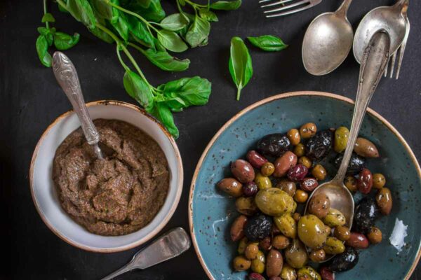 Homemade vegan olive tapenade alongside a bowl of mixed olives