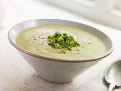 A bowl of our chilled avocado soup recipe topped with green onions and turmeric