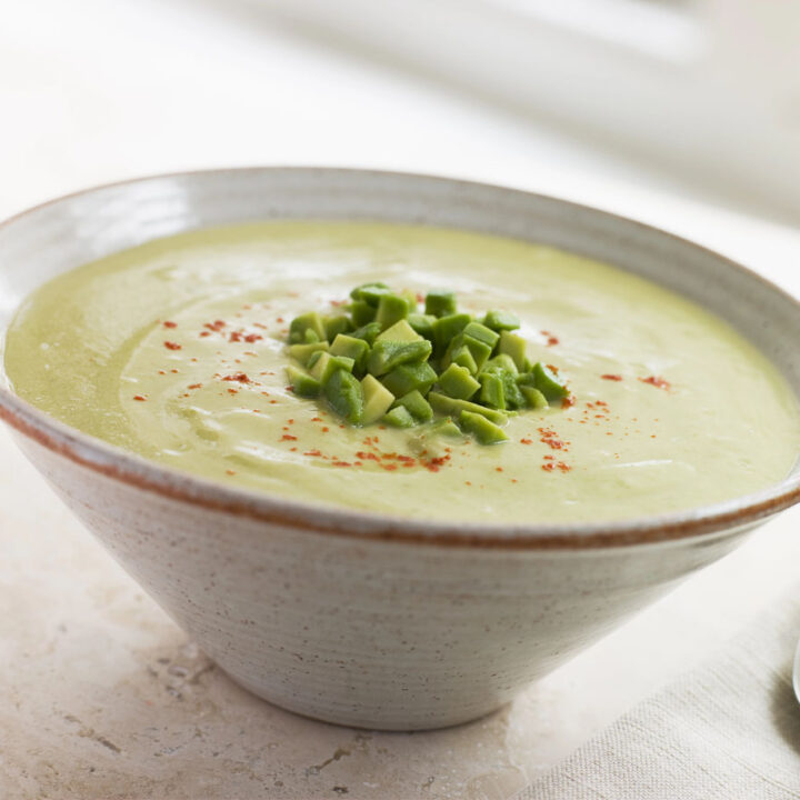 A bowl of our chilled avocado soup recipe topped with green onions and turmeric