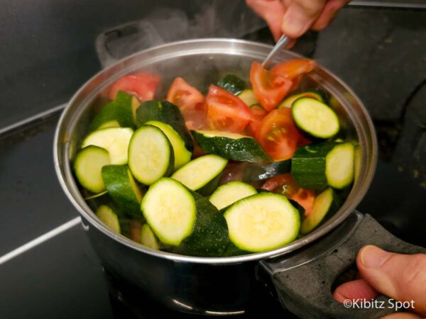 Zucchini and tomatoes in a sauce pan with olive oil and lemongrass, the first step in our Vietnamese zucchini recipe.