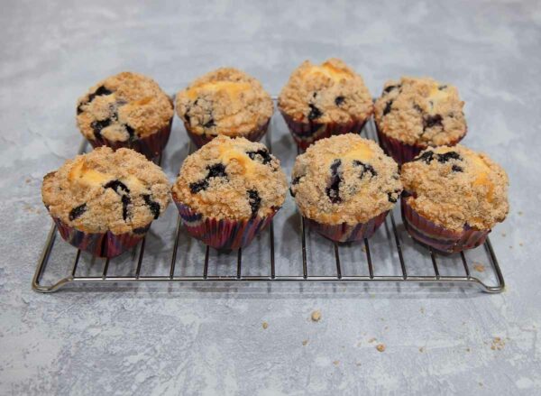 Gluten-free blueberry muffins topped with streusel on a cooling rack