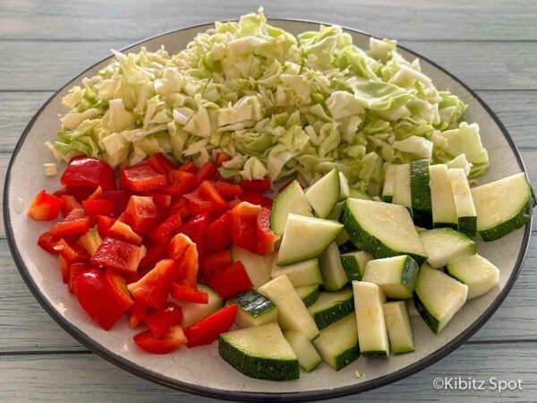 A plate of chopped cabbage, bell pepper, and zucchini for stir frying